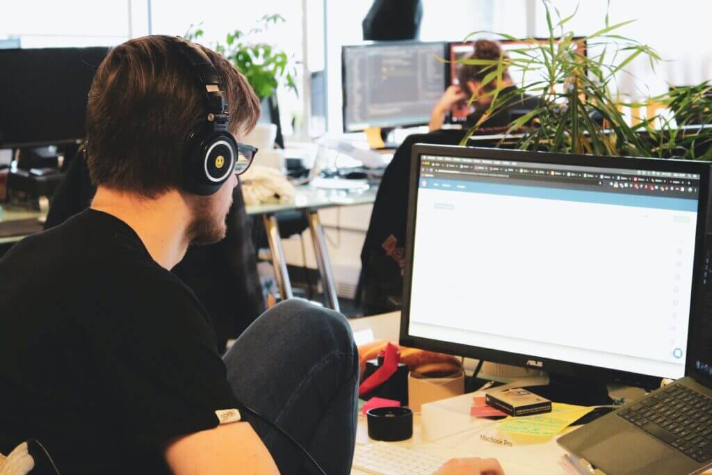 it developer in black tshirt sitting in front of desk working on B2B integration solutions - multishoring