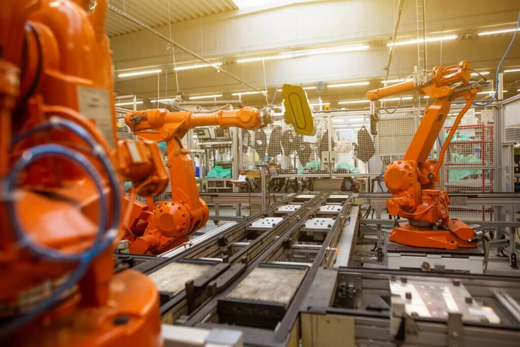 orange robotic arms at a factory - software for manufacturing - multishoring