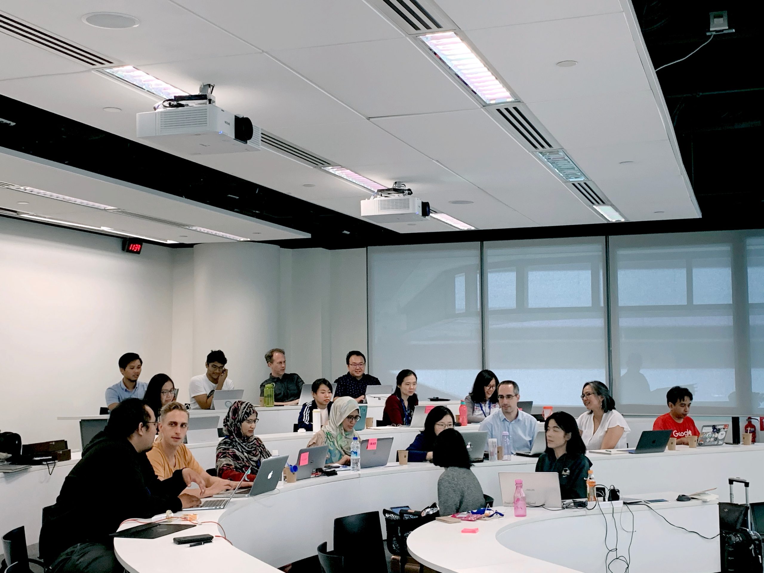 students with laptops sitting in a modern classroom - educational software development services Multishoring