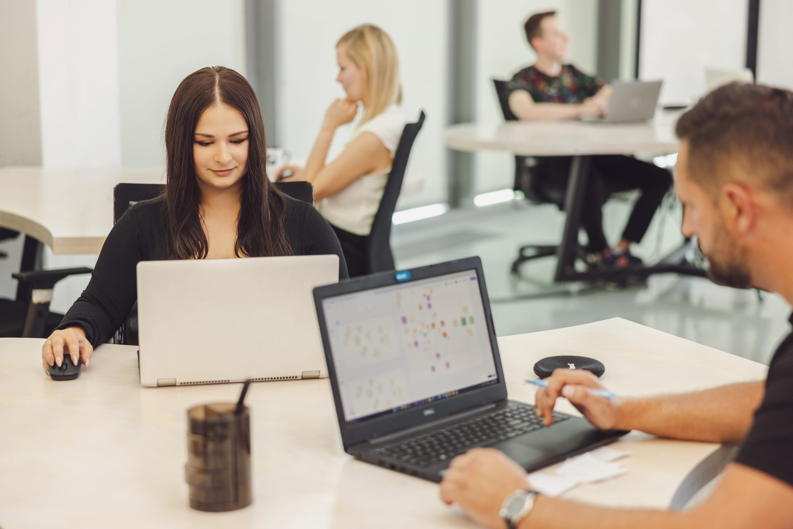 Multishoring data visualization consultants analyzing complex network graphs and business intelligence dashboards on a laptop in a modern office.