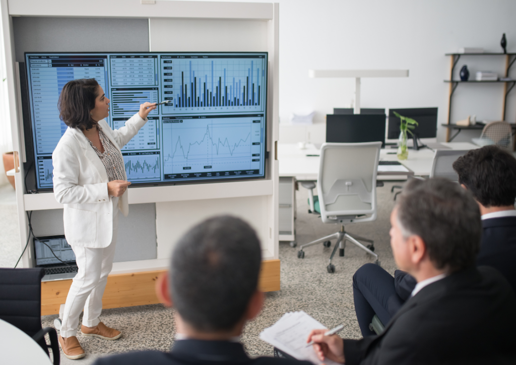 Data consultant presenting a Power BI dashboard to executives, showcasing how modern data architecture services enable real-time data analysis and strategic decision-making.