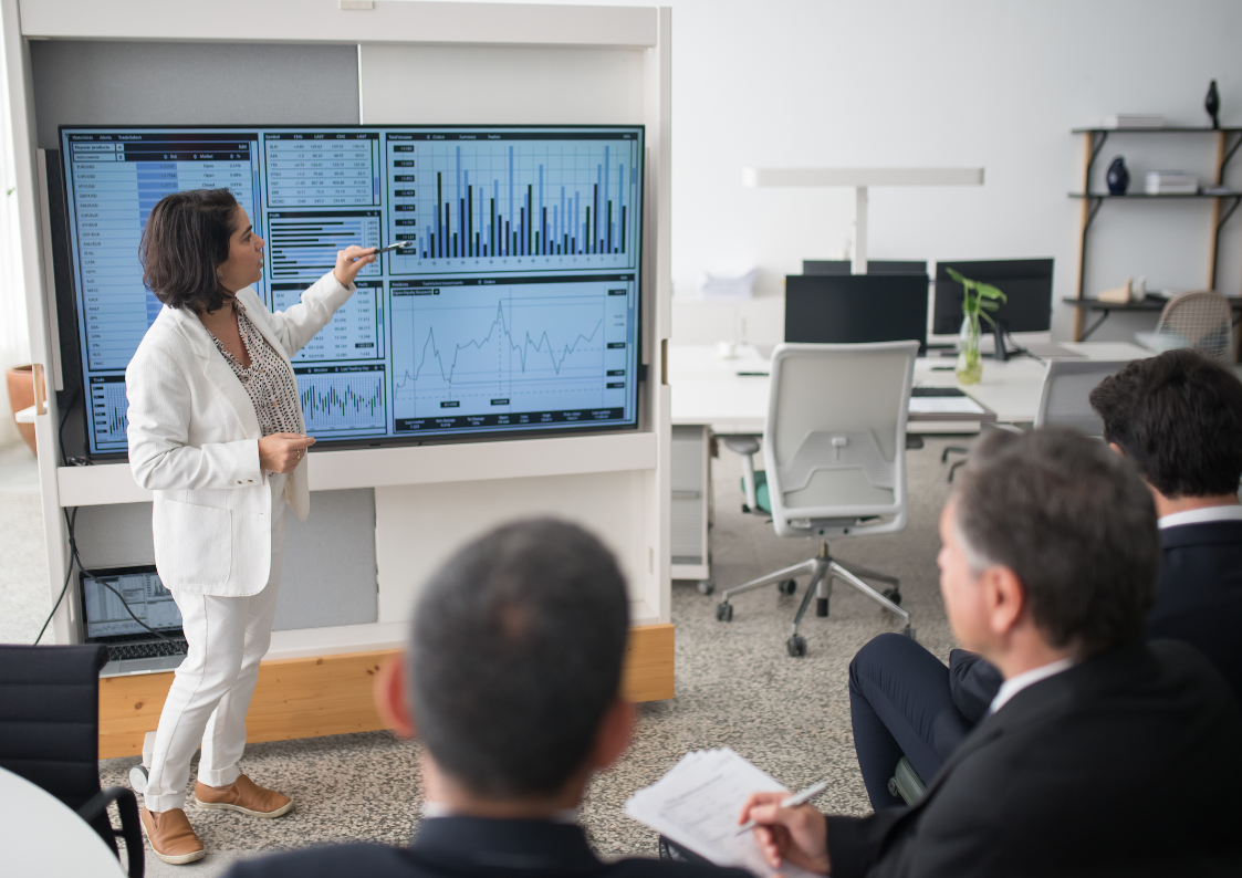 Data consultant presenting a Power BI dashboard to executives, showcasing how modern data architecture services enable real-time data analysis and strategic decision-making.